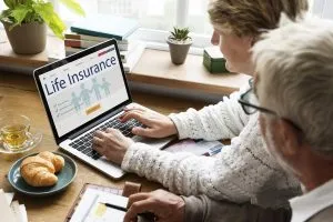 An older couple look at information about life insurance on their laptop.