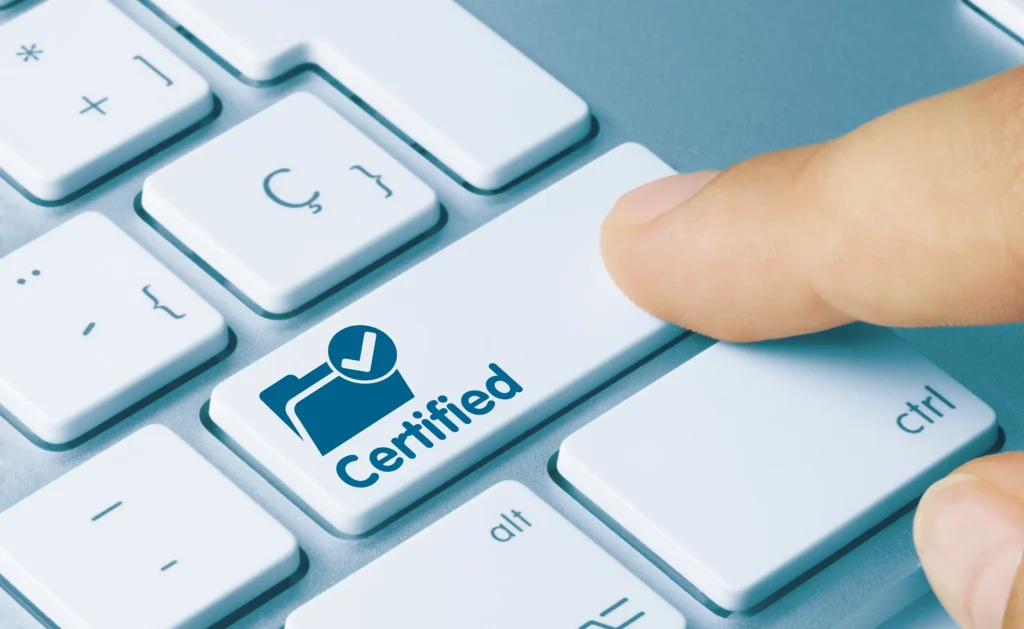 A finger presses a button on a computer keyboard. The button has a folder with a tick and the word ‘certified’ on it. The person pressing the button has plain language certified documents.